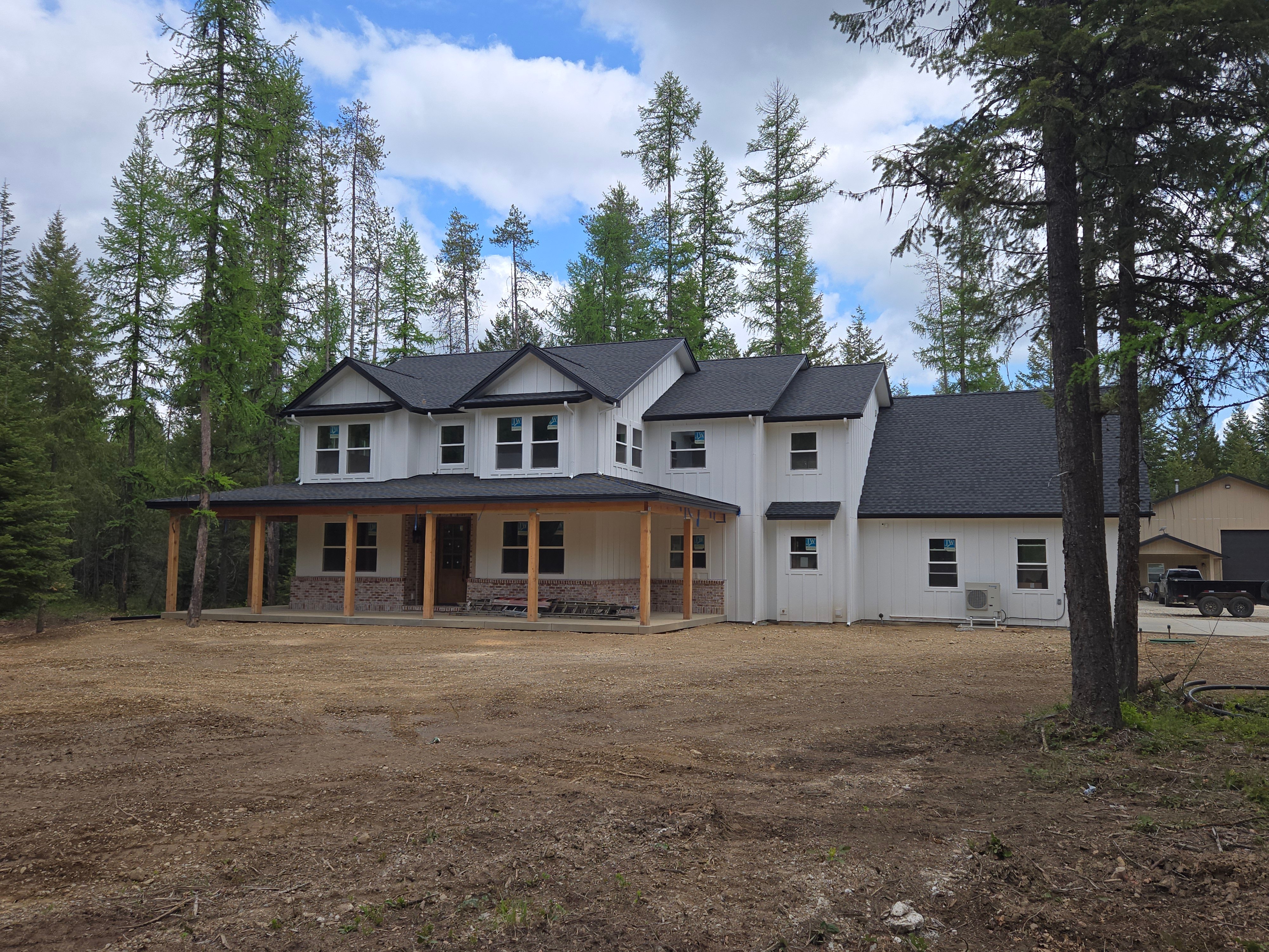 Large custom home with modern farmhouse design featuring white siding and natural wood accents