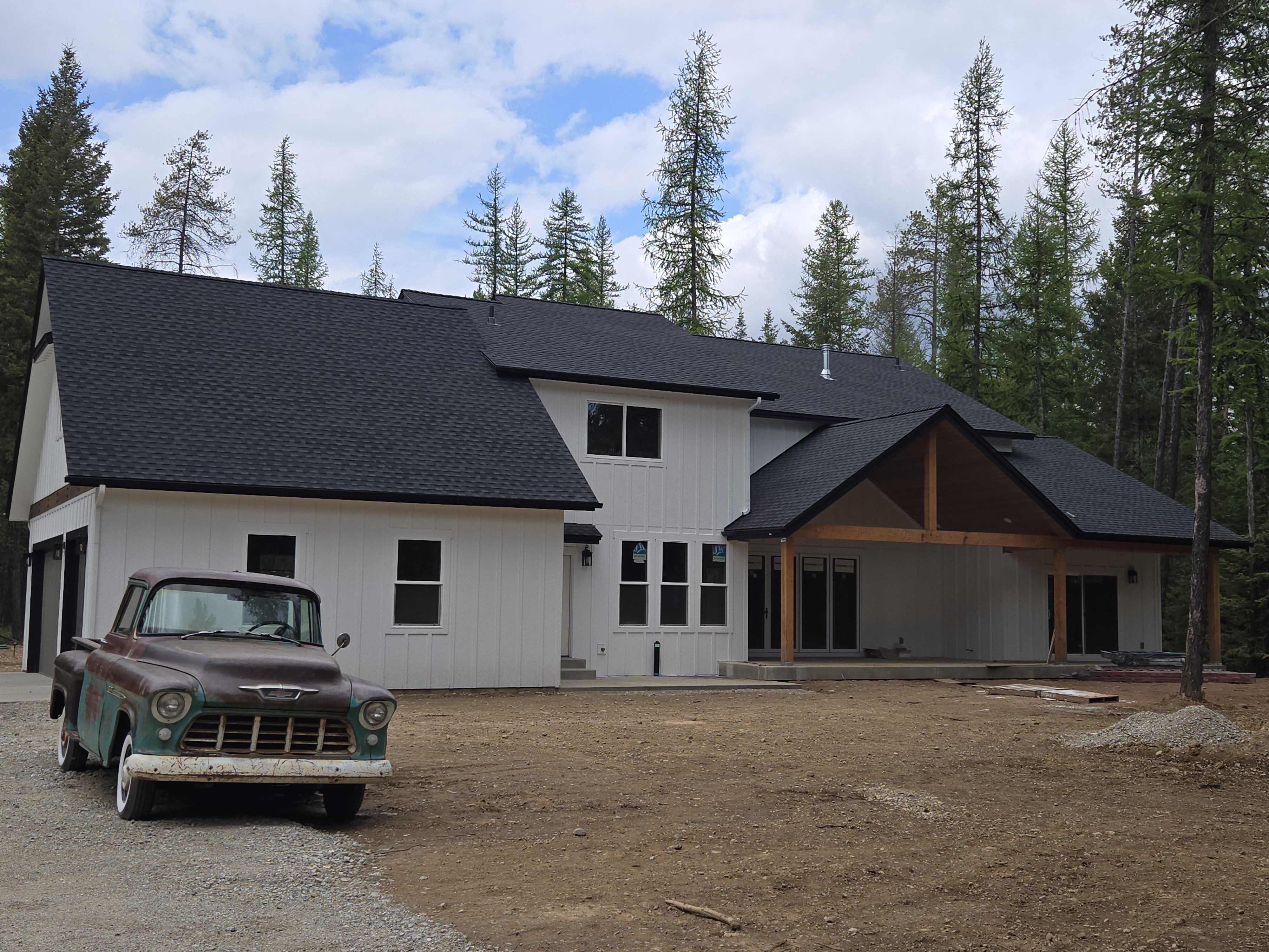 Custom home with vintage truck, showcasing a rustic barndominium style in a rural North Idaho setting