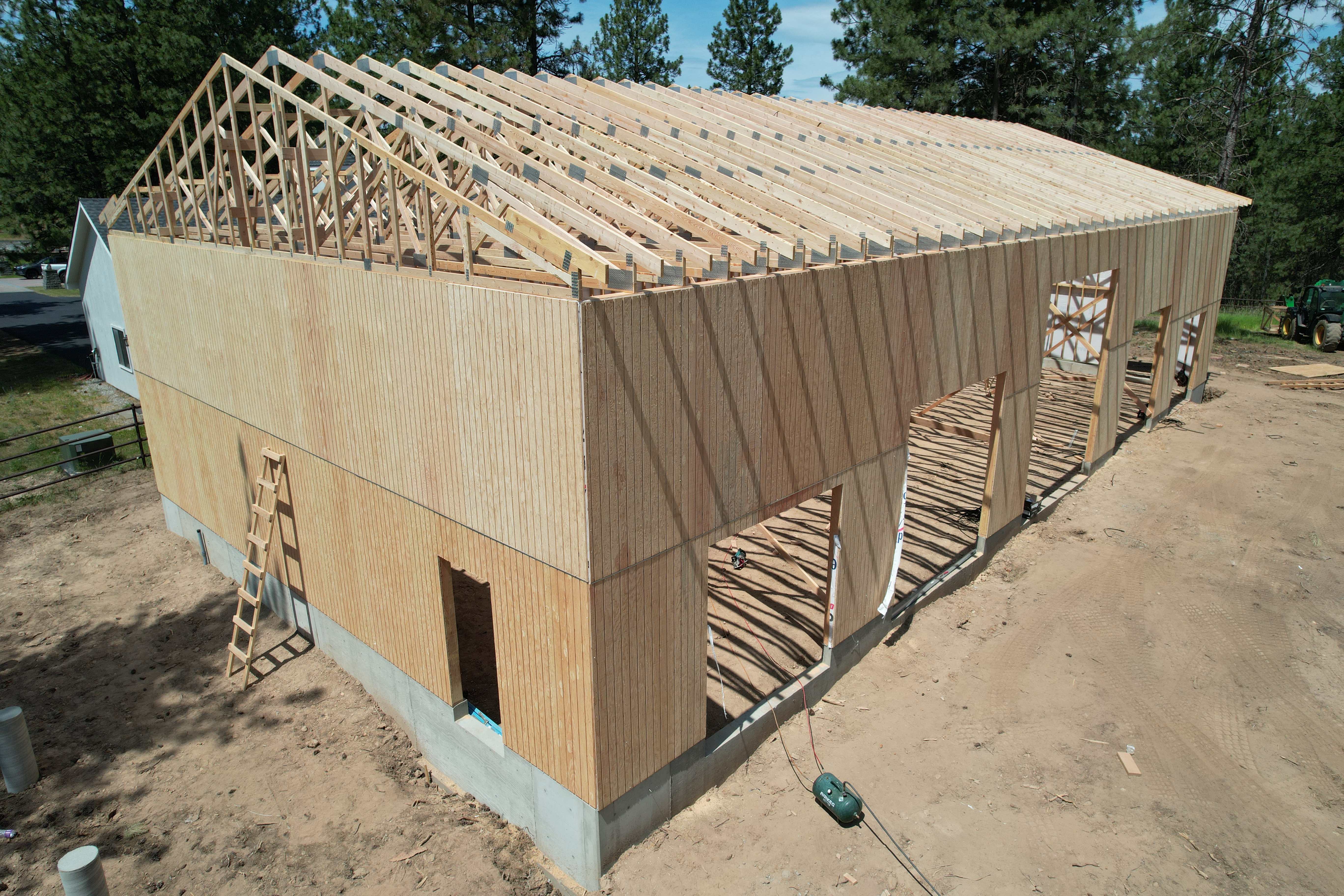 Large custom shop during the stick-built framing phase, showing quality wood trusses and construction.
